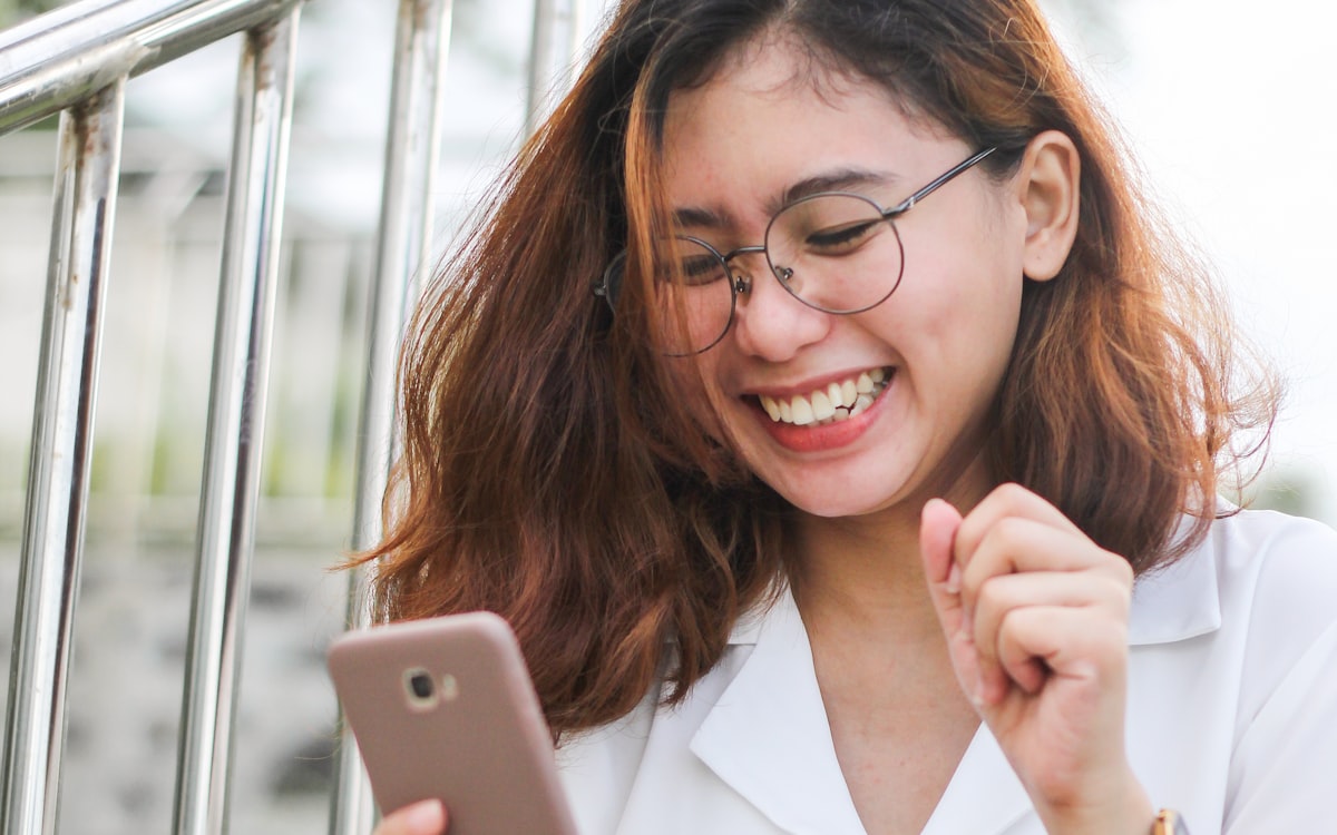 Jovem rindo enquanto usa o celular — o brasileiro está sempre com o WhatsApp aberto