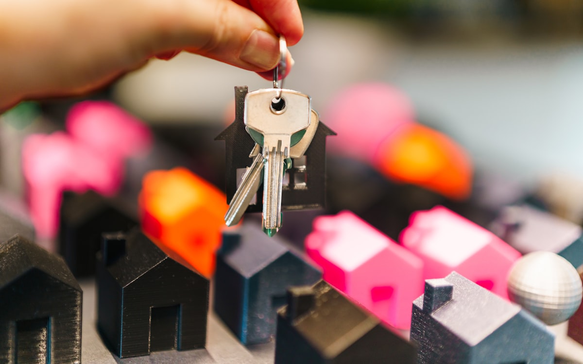 Mão segurando chaves sobre miniaturas de casas — qualificar lead de imóvel pelo WhatsApp na imobiliária